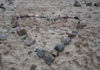 Ein Herz aus Steinen im Sand.