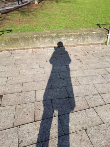 Schattenbild einer Person auf Kopfsteinpflaster.